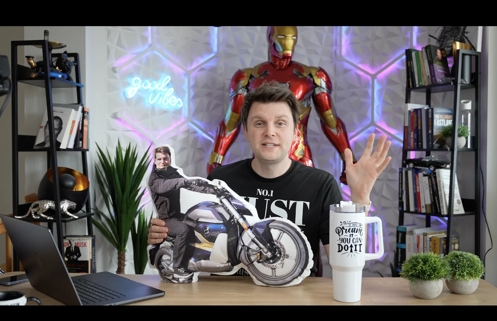 Frank zeigt in seinem YouTube-Studio Print-on-Demand-Produkte: ein personalisiertes Motorrad-Kissen und einen bedruckten Becher